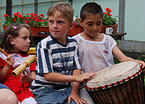 Kinder vor dem Barackenkloster beim Musizieren